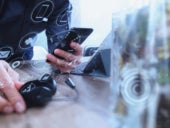 Man using VOIP headset with digital tablet computer docking keyboard and smartphone.