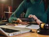 A lawyer studying a case while looking through her tablet.