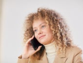 A curly-haired woman talking on a cell phone.