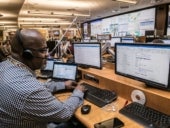 A contact center agent working at his desk with multiple screens in front of him.