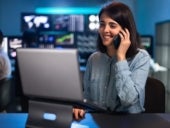 Woman working in office using laptop and talking on the phone with client