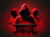 Faceless hackers in red shadows using laptops.