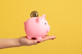 Close up side view portrait of woman hand holding piggy bank with golden coin.