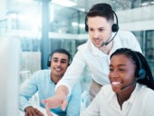 A call center manager helping two employees at their call stations.