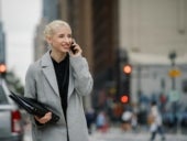 Cheerful businesswoman talking on smartphone in town.