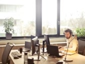 Man with headphones facing computer monitor.