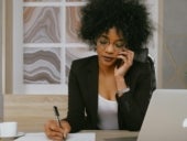 Woman in black blazer holding smartphone.