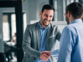 Business persons handshaking in an office setting.