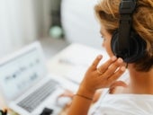 Person in white shirt holding black headphones.