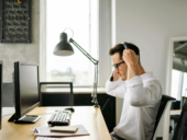 Person putting on a headset sitting in front of their computer in an office setting.