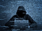 Silhouette of a hacker in hood using a laptop from numerical data.