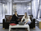 Two people talking and looking at a laptop in an office.