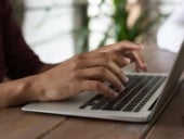 Someone's hands coming into frame, typing on a laptop.