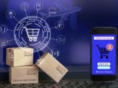 Smartphone runs an online shopping app with cardboard boxes on notebook keyboard.