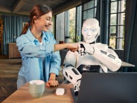 Robot and woman working on laptop in office