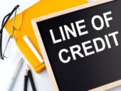 LINE OF CREDIT text on the blackboard with notepad , pen, pencil