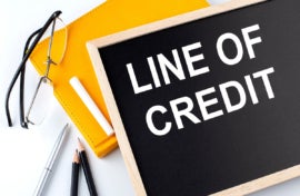 LINE OF CREDIT text on the blackboard with notepad , pen, pencil
