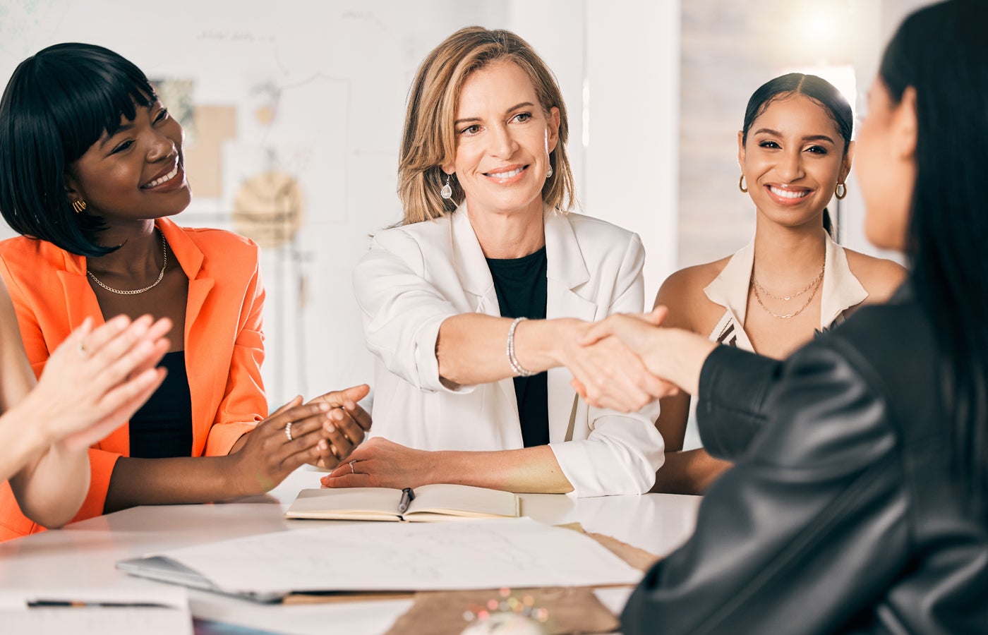 A group of women handshaking on a business deal.