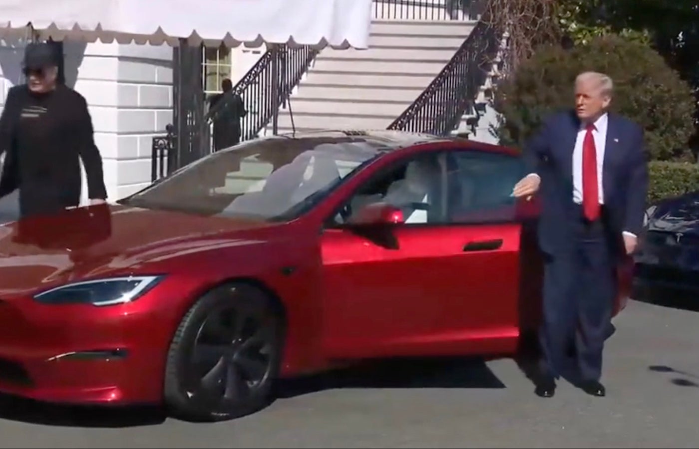 President Donald Trump getting out of the Tesla he purchased. He is accompanied by Tesla CEO Elon Musk.