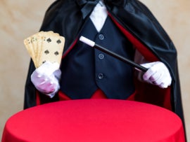 Illusionist holding magic wand and playing card.