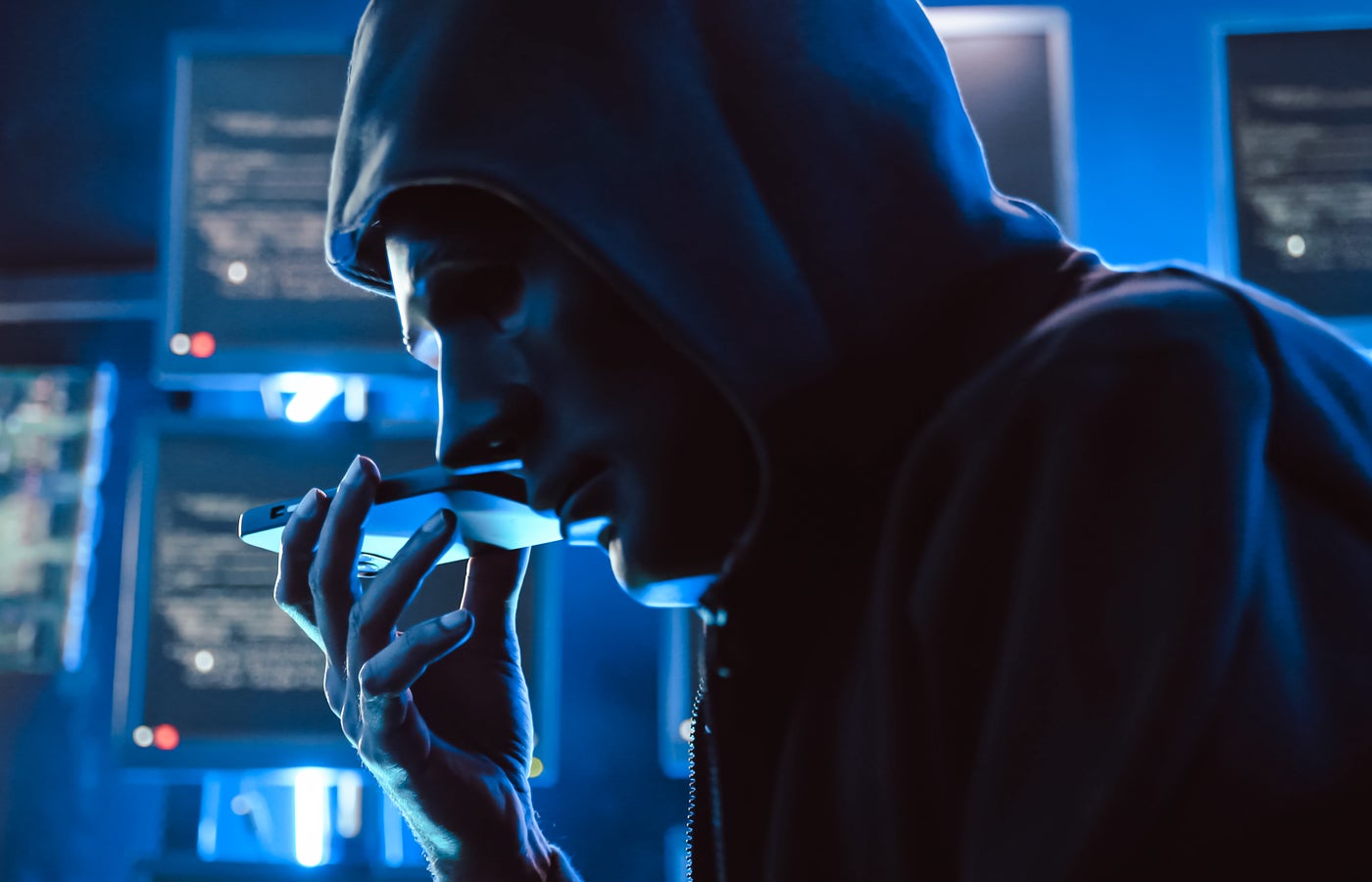 A hacker wearing a mask to cover his face is using computer to hack data to get ransom from victims.