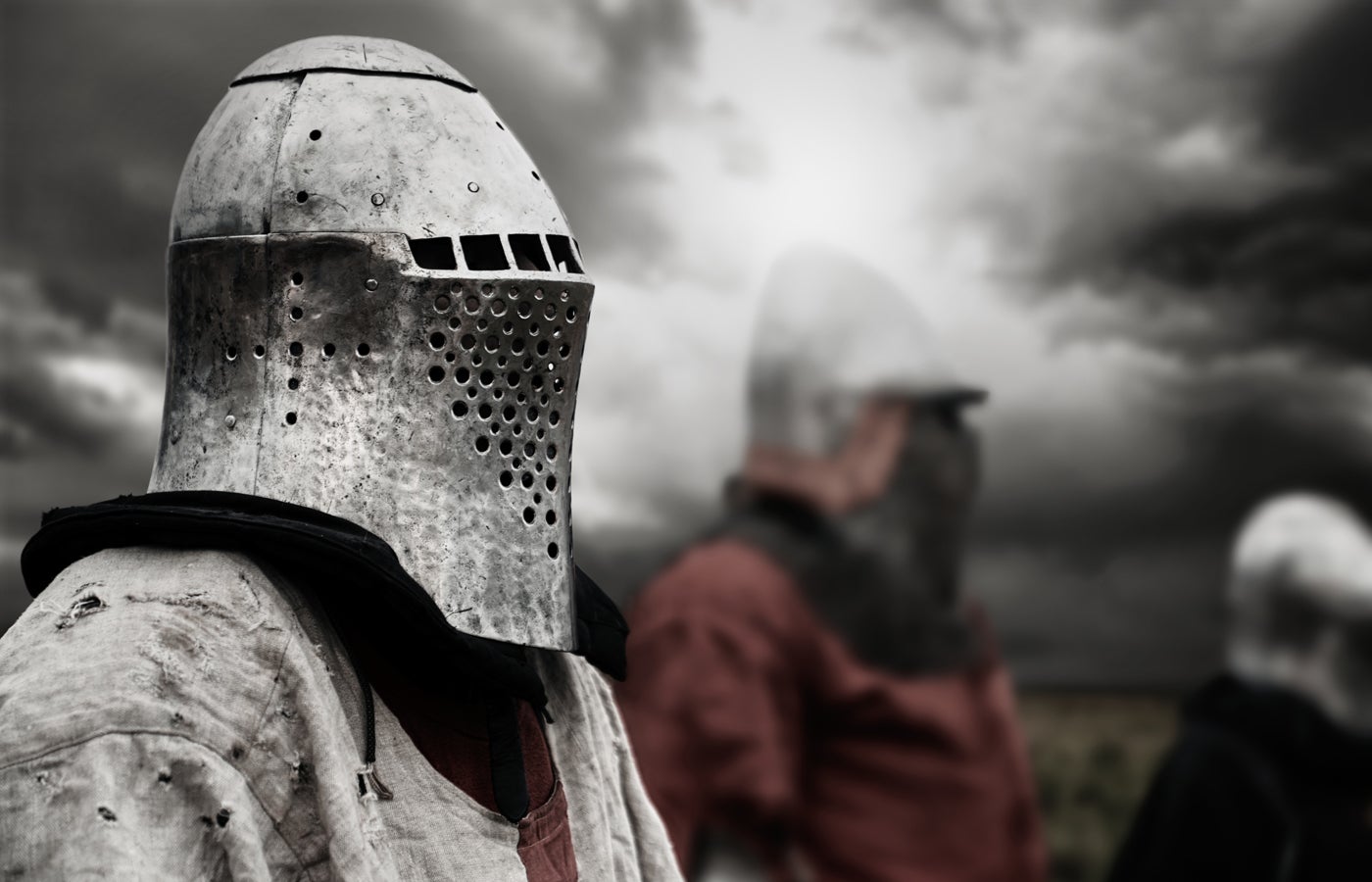 Side view of medieval knight in iron helmet posing.