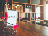 Mobile Phone with Shopify Logo on Screen Placed on a Small Shopping Cart
