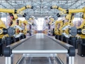 Automated robotic arms with grippers aligned on both sides of a conveyor belt inside a modern industrial warehouse.