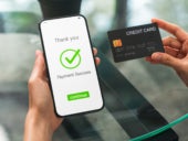 Woman holding credit card with successful payment screen and shopping on smartphone.