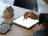 Businesspeople use a pen to write on a tablet with model house