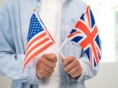 Stock photo of a person holding small US and UK flags.
