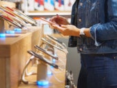 Young woman chooses a smartphone in an electronics store.