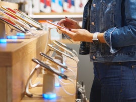 Young woman chooses a smartphone in an electronics store.
