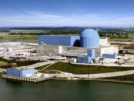 Nuclear power plant with blue dome near water.