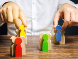 A man playing with colored wooden human blocks.