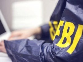 Person using a laptop with FBI written on the arm sleeve.