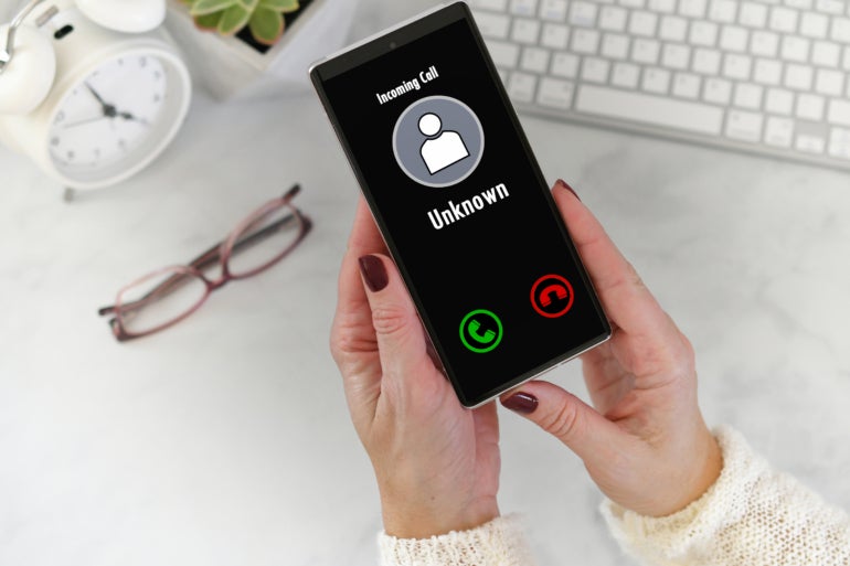 A woman holding a phone, while an unknown caller is calling.