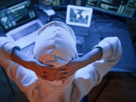 Young professional female hacker is indoors by computer with lot of information on displays.