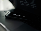 OpenAI app on phone placed on top of a laptop.