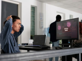 Nervous IT programmer having security breach alert on computer display.