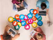 Young friendly people in casualwear sitting by multi-color papers with icons