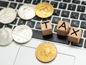 Bitcoin and next to wooden with TAX letters. Bitcoin taxation concept