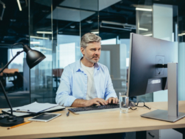 Experienced worker works at the computer in a modern office.