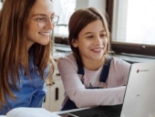 Woman teaching a girl using a chromebook.