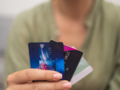 A close up picture of a woman holding three credit cards.