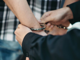 Police officer puts handcuffs on a suspect.