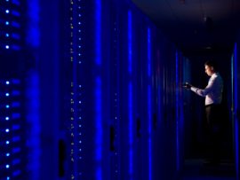 Side view of an IT technician working In the aisle of a data center Room