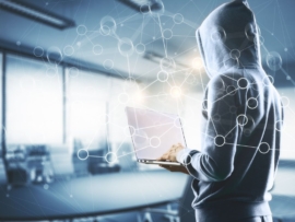 A person in hoodie working on a laptop.
