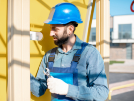 Workman in uniform mounting ladder for kids playing on the playground outdoors.