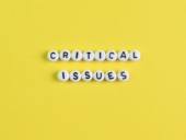 Alphabet beads with text CRITICAL ISSUES isolated on a yellow background
